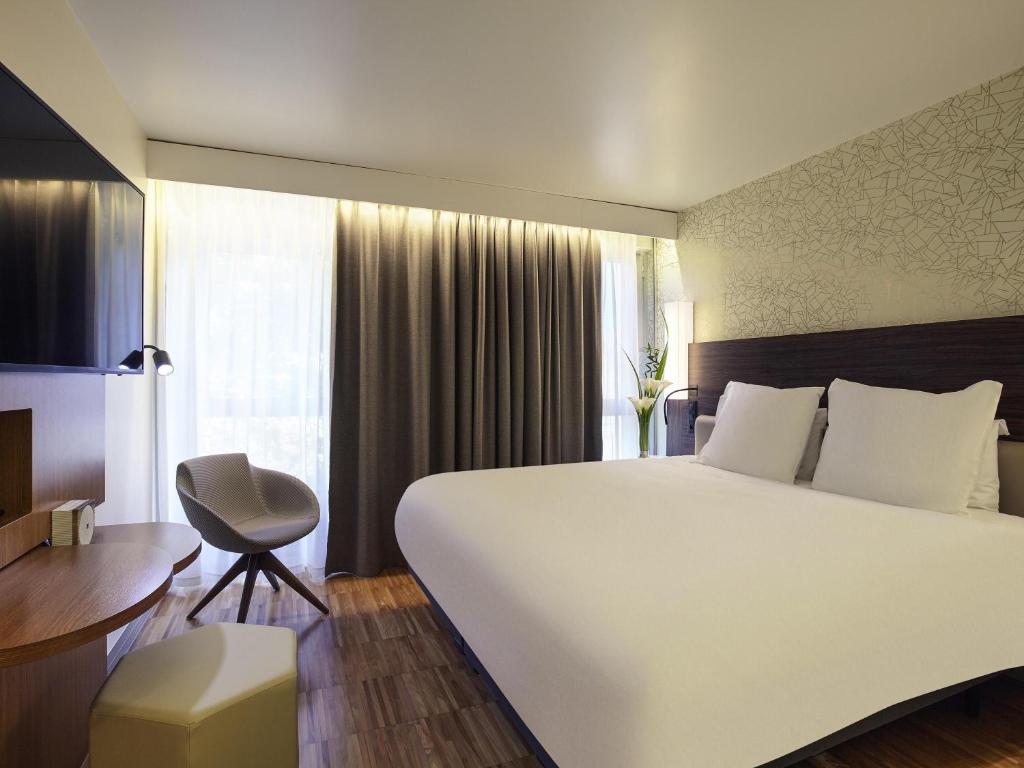a bedroom with a large white bed and a chair at Mercure Paris Arc de Triomphe Etoile in Paris