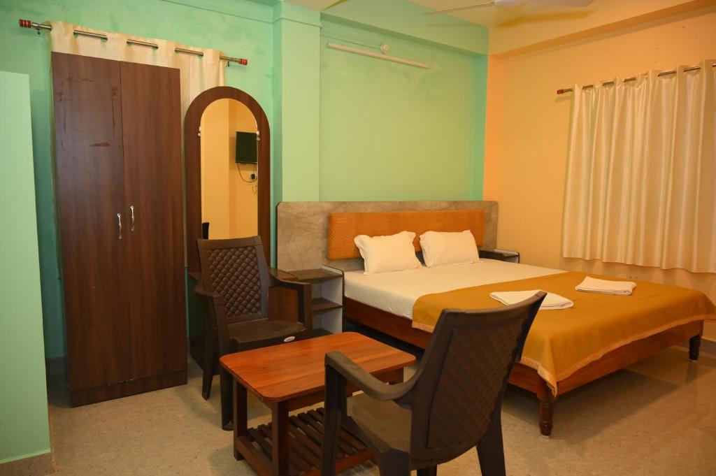 a bedroom with a bed and a table and chairs at ROYAL SEAVIEW RESIDENCY in Port Blair
