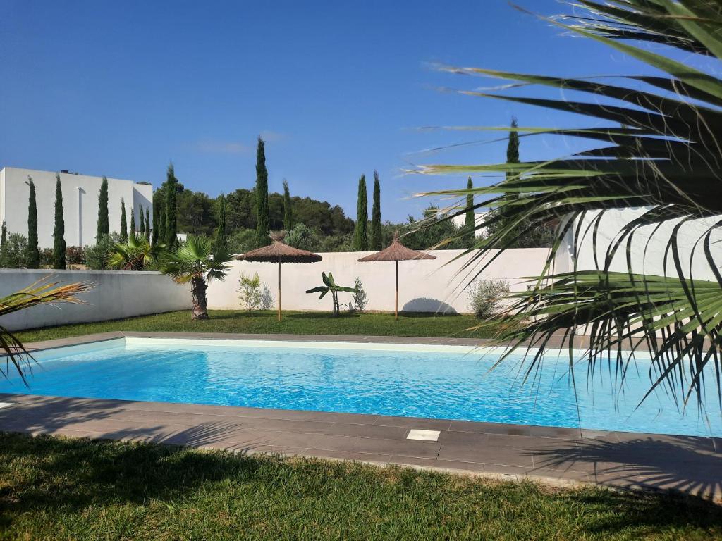 a swimming pool in a yard with umbrellas at location Phoebé dans la propriété Elaia in Tourouzelle