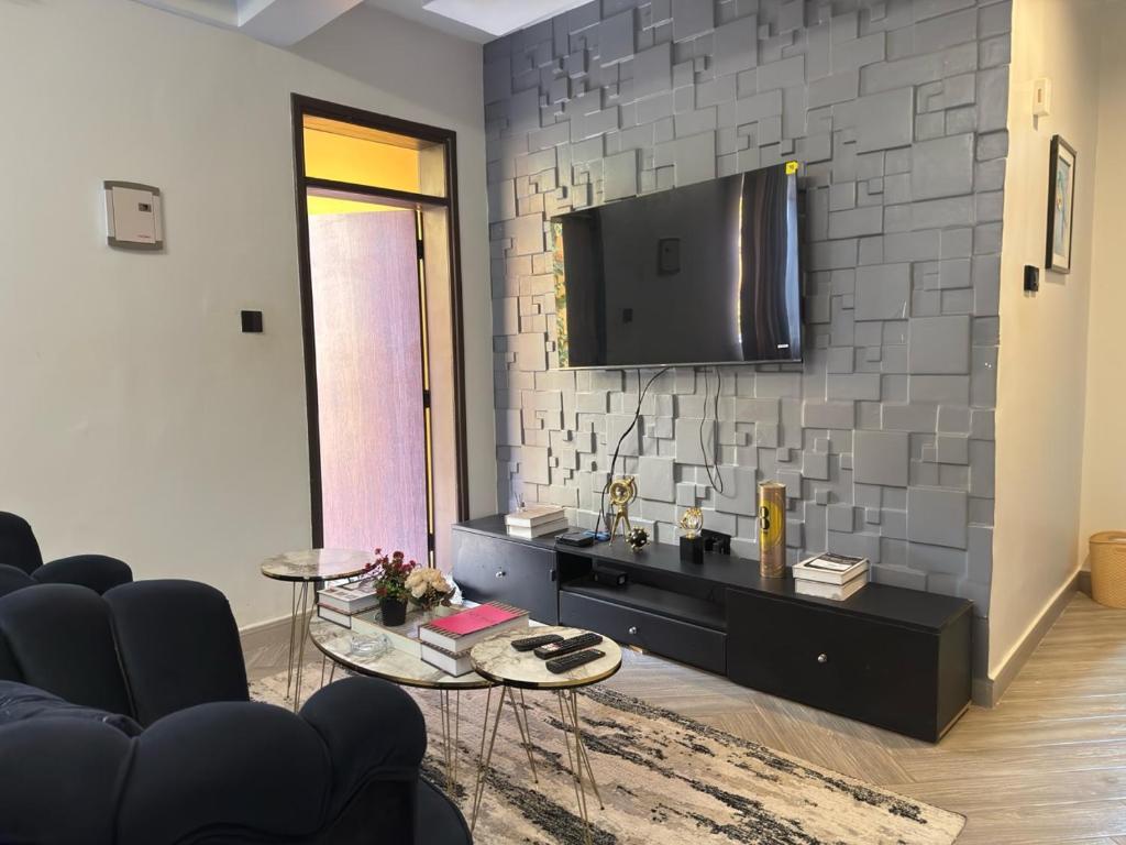 a living room with a tv on a brick wall at Chic and Cozy studio Kyanja in Kampala