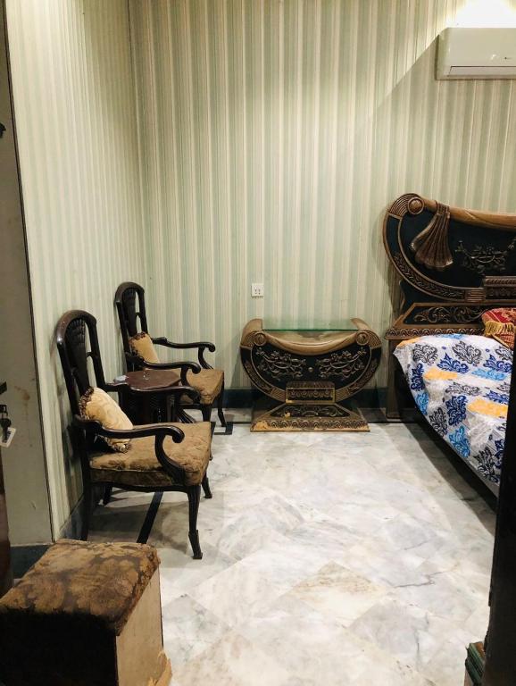 a room with two beds and chairs and a table at 2 Furnished rooms in a house in Faisalabad