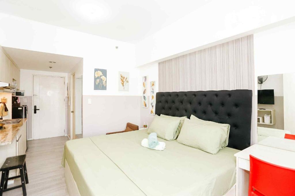 a bedroom with a large white bed with a black headboard at Sky's Cozy Nest in Cebu City