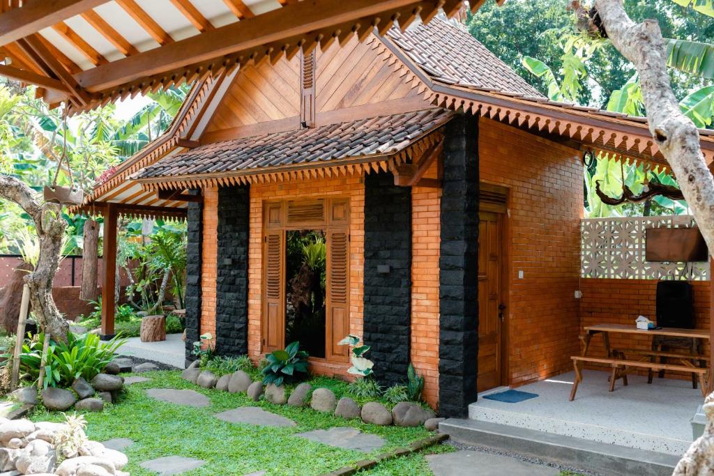 une maison en bois avec une table dans un jardin dans l'établissement Homestay Pondok Jepun Banyuwangi, à Dadapan