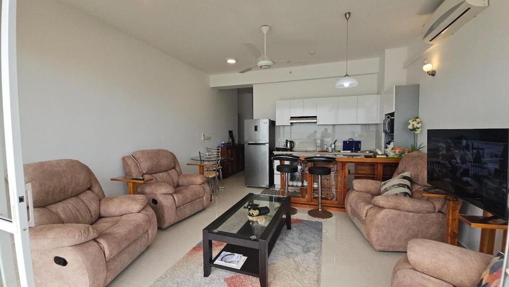 a living room with couches and a table and a kitchen at Ocean Paradise Luxury in Nikawatawana