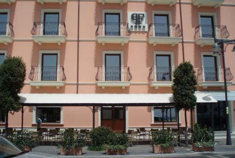 een roze gebouw met tafels en stoelen ervoor bij Palazzo Foti Hotel in Crotone
