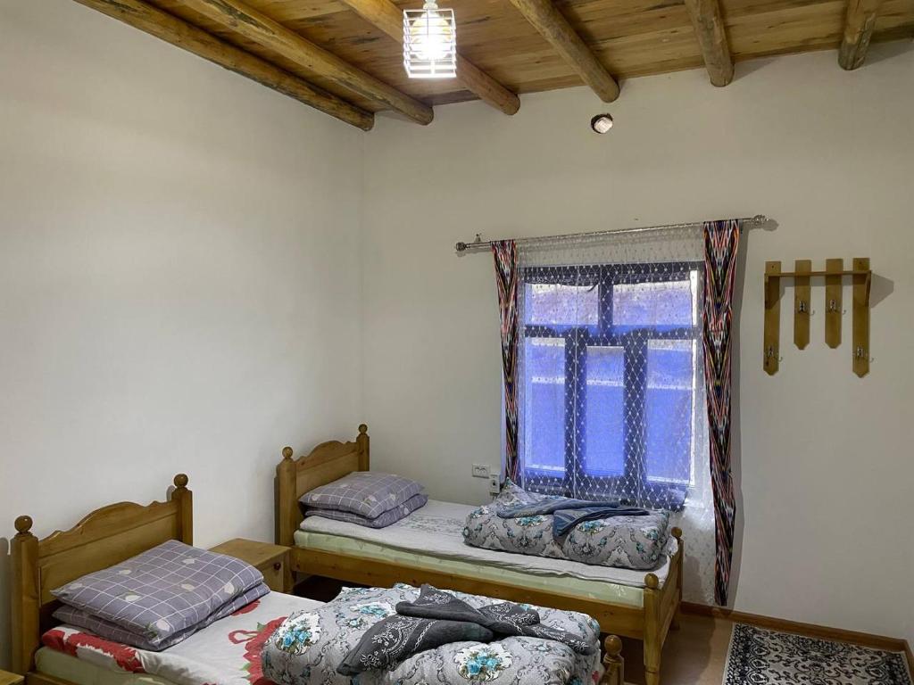 twee eenpersoonsbedden in een kamer met een raam bij Firdavs guest house in Yukary-Ukhum