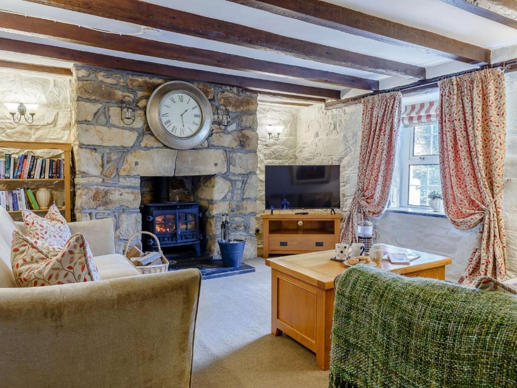 a living room with a stone fireplace and a clock on the wall at 3 Bed in Newquay 82369 in Mitchell