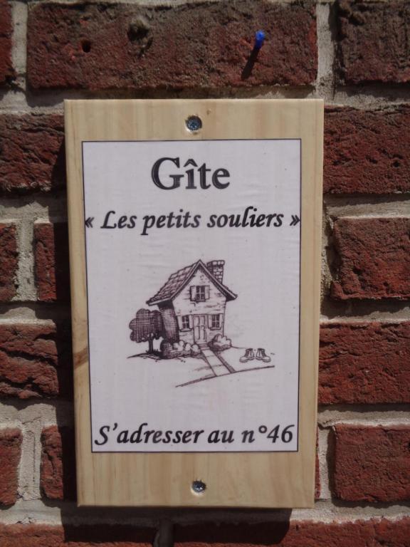 un cartel en una pared de ladrillo con una foto de una casa en Les Petits Souliers, en Lestrem