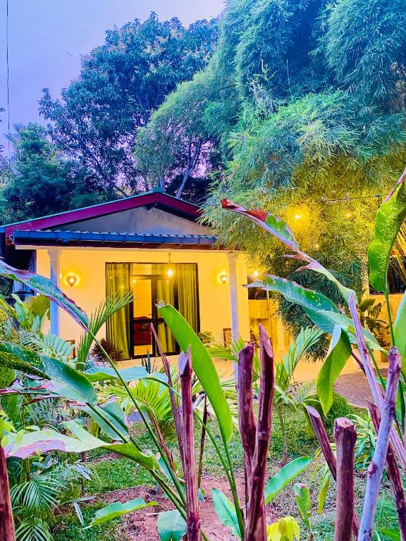 a small yellow house in the middle of a garden at TIKITIBE Villa & Restaurant in Hiriketiya