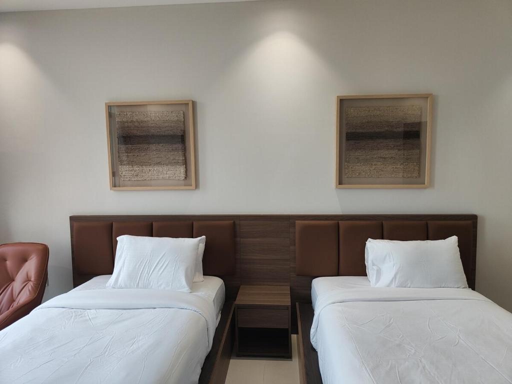 dwa łóżka ustawione obok siebie w pokoju w obiekcie Muscat City Stay - 2BR Apt 308 near Grand & Avenue Mall w mieście Ghukra