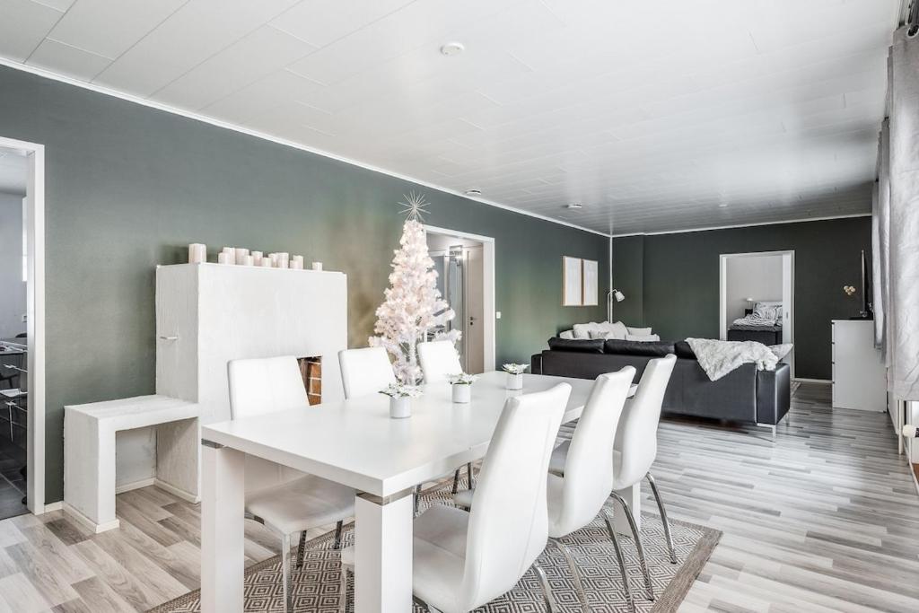 a dining room with a white table and white chairs at Santa's choice for Aurora hunters , Sauna and jacuzzi in Rovaniemi