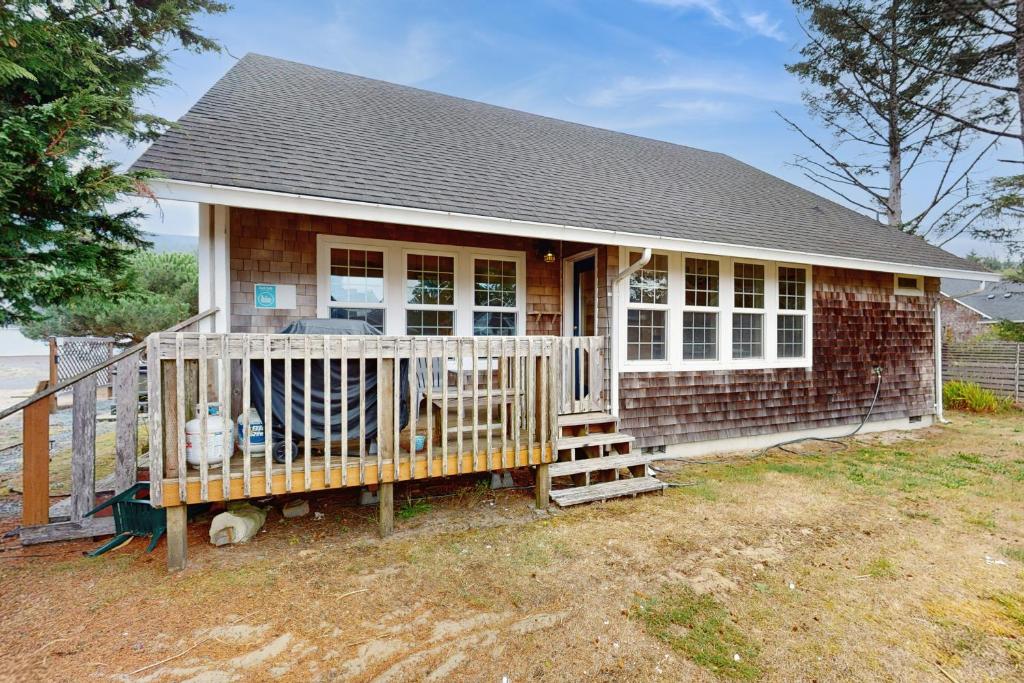 a small brick house with a porch and a fence at Windsong in Rockaway Beach