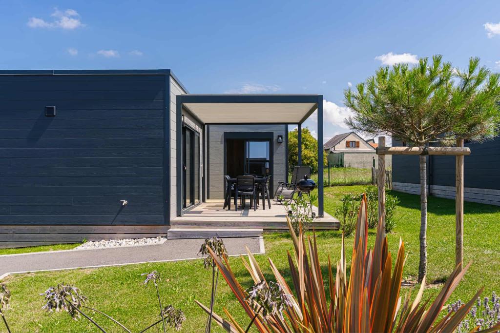 a home with a black siding and a patio at Omaha in Asnelles