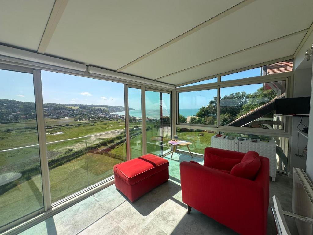 Una sala de estar con un sofá rojo y una gran ventana. en Le tableau, en Pourville-sur-Mer