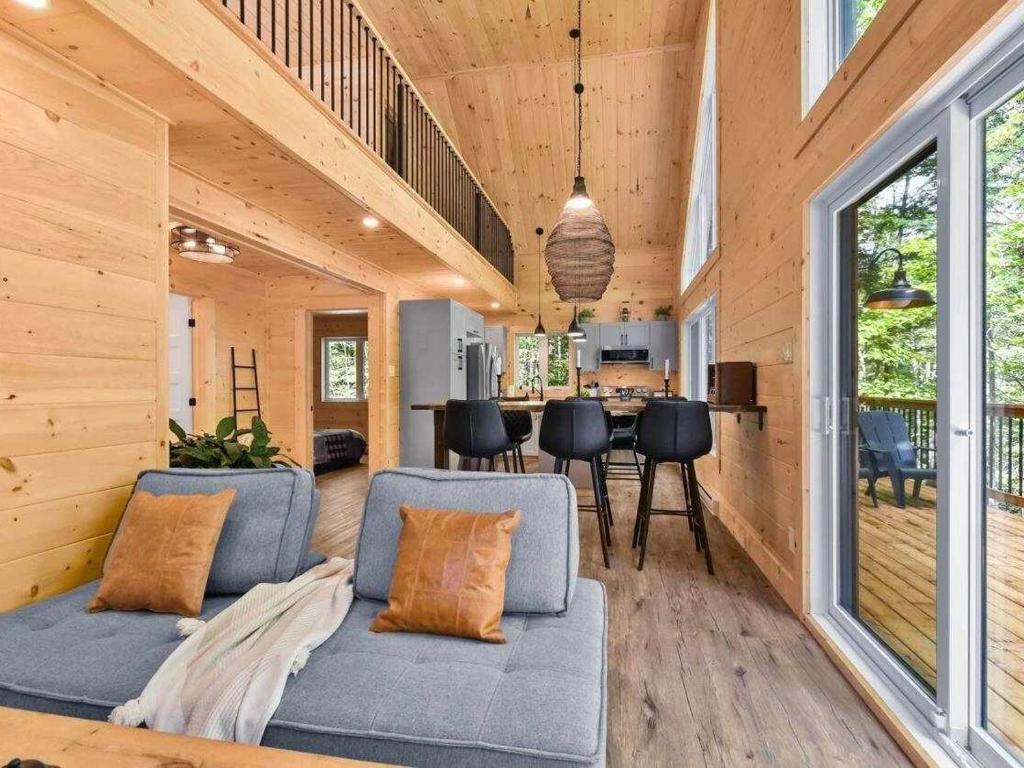 a living room with a couch and a dining room at NEW Chalet des pins - lake access in Saint-Alphonse-Rodriguez