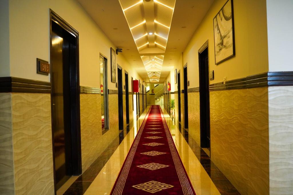 a hallway with a red carpet in a building at Sapphire Stays Hotel and Restaurant Peshawar in Peshawar