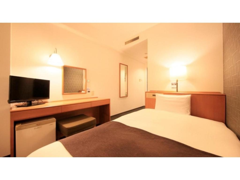 a hotel room with a bed and a desk with a television at Smile Hotel Tokyo Ayase Ekimae - Vacation STAY 14730v in Tokyo