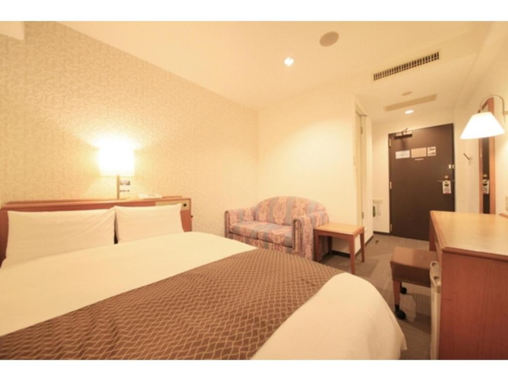 a hotel room with a bed and a chair at Smile Hotel Tokyo Ayase Ekimae - Vacation STAY 14737v in Tokyo