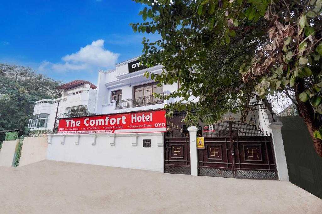 a white building with a red sign on it at Super Hotel O The Comfort in Kānpur