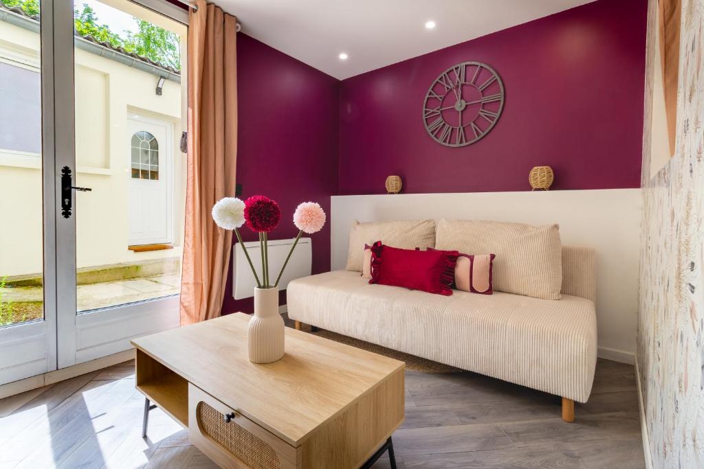 a living room with a couch and a vase with flowers at Siloé - Balnéo - Stationnement gratuit dans la rue- Gare 10 min à pied in Troyes
