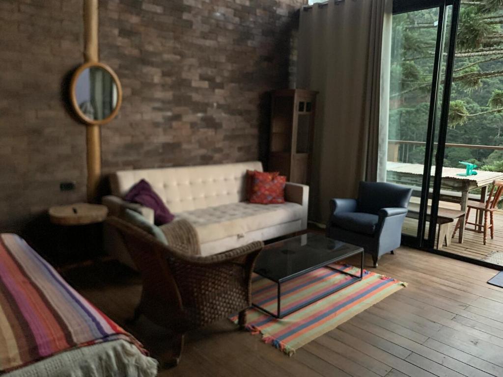 una sala de estar con un sofá y una silla en Refugio Araucária - Gonçalves Mg, en Gonçalves