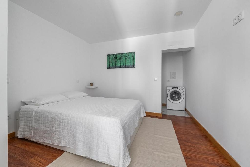 a white bedroom with a bed and a washing machine at Quatro Ponto Cinco in Caldelas