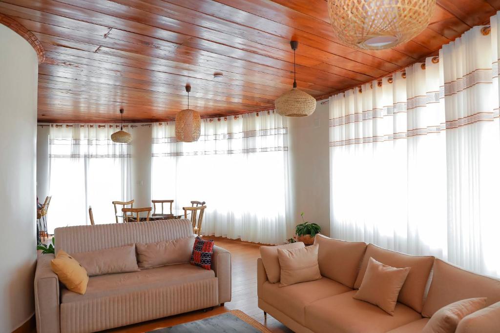a living room with two couches and large windows at African-style villa with lake view, sleeps 12 in Rwamagana