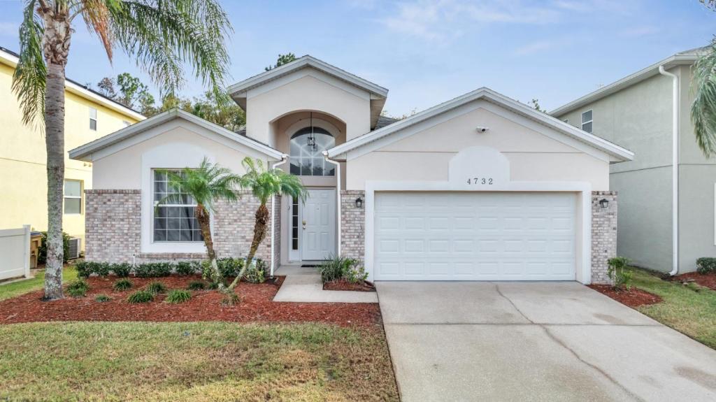 基西米Disney Getaway Pool Gated Resort Near Parks的一座拥有白色车库和棕榈树的房子