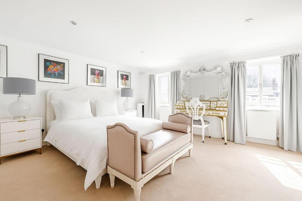 a white bedroom with a white bed and a chair at Large Belgravia Georgian Mansion House in London