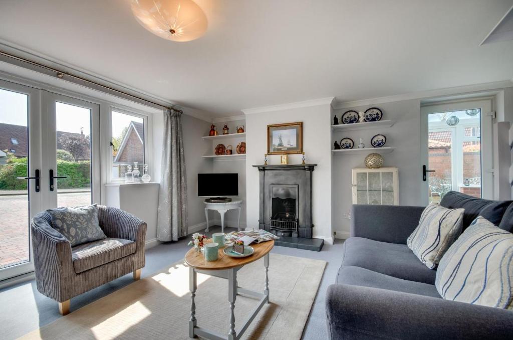 een woonkamer met een bank en een open haard bij Garden Cottage in Holt
