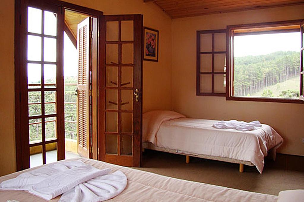 a bedroom with two beds and a window at Alpenhaus Pousada in Campos do Jordão