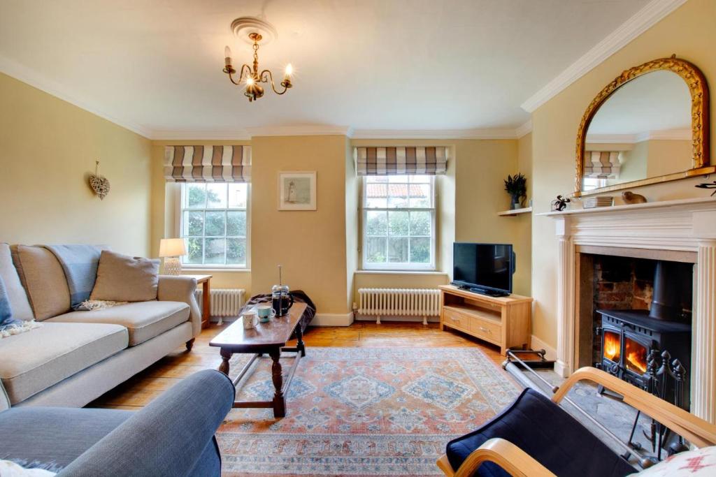 un soggiorno con divano e camino di Holly Cottage a Cromer
