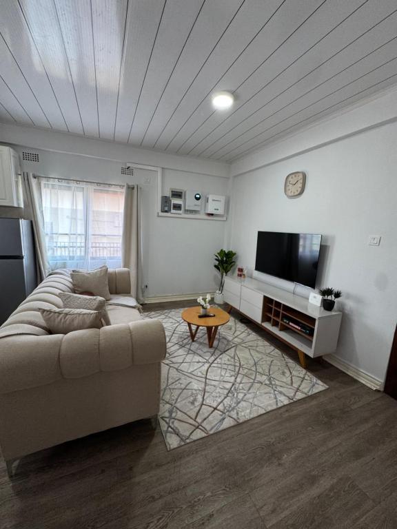 ルサカにあるThe Mallside Apartmentsのソファと薄型テレビのあるリビングルーム