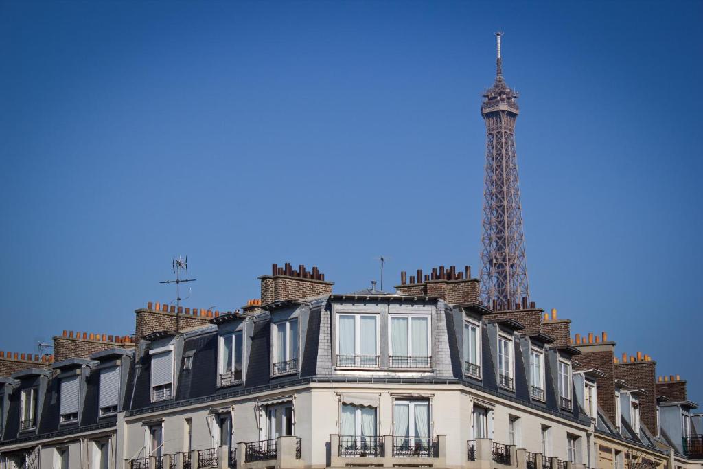 巴黎的住宿－埃菲爾小盧浮宮酒店，公寓大楼的背景是通讯塔