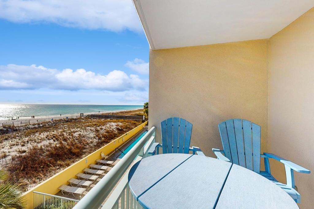 Un balcón con mesa y sillas y la playa. en Pelican Isle 209, en Fort Walton Beach