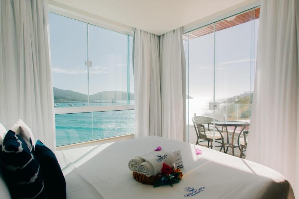 a room with a bed and a view of the ocean at Canto da Canoa Suítes I in Arraial do Cabo