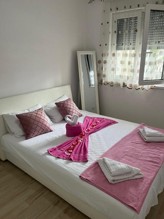 a white bed with pink sheets and a box on it at Elly in Modriča