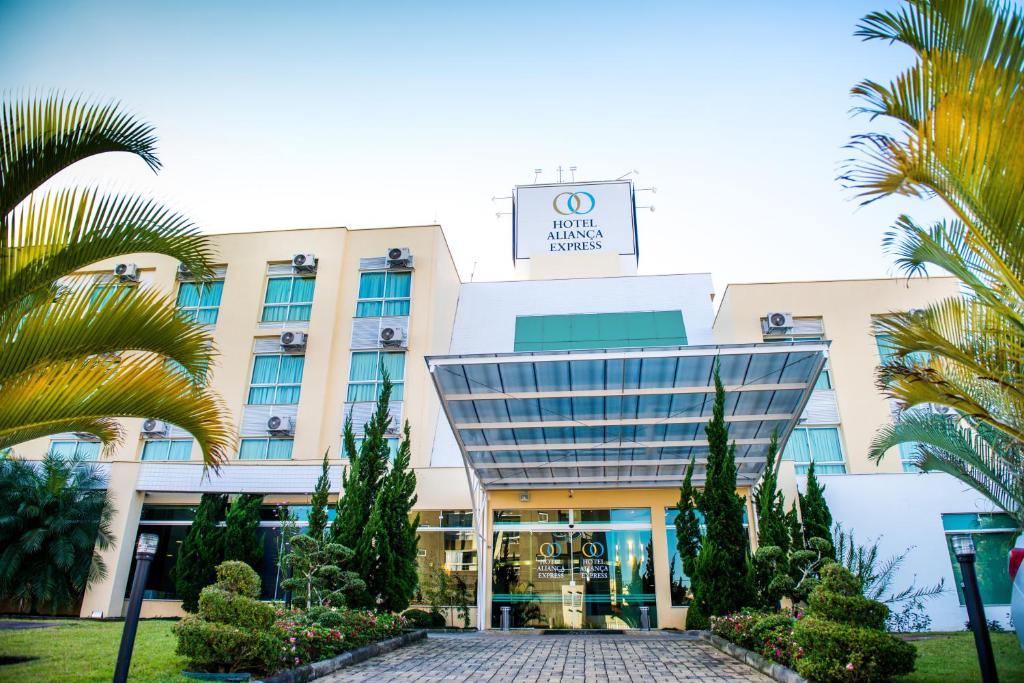 a building with palm trees in front of it at Hotel Aliança Express in Rio do Sul