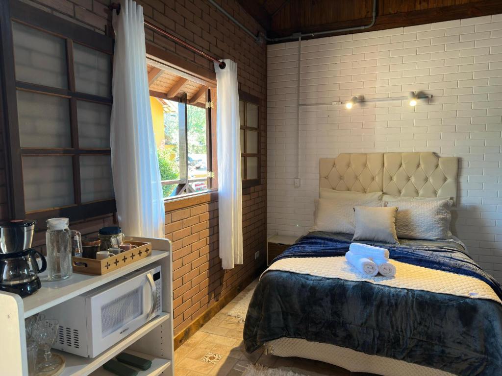 een slaapkamer met een bed, een tv en een raam bij Flat Girassol Santo Antônio do Pinhal in Santo Antônio do Pinhal