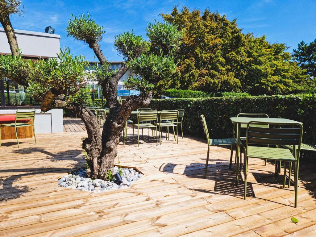 a table and chairs and a tree on a patio at ibis Caen Porte d’Angleterre in Caen