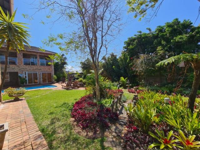 a garden with flowers and plants in front of a house at DuneSide Guesthouse in Richards Bay