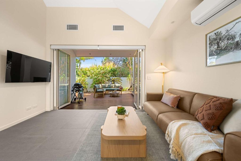 ein Wohnzimmer mit Sofa und Tisch in der Unterkunft Beachside Bungalow on Shelly Beach in Caloundra