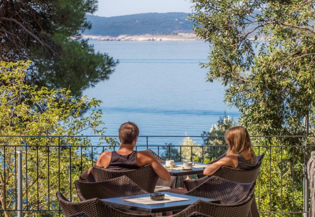 un hombre y una mujer sentados en una mesa mirando el agua en Bed and Breakfast Saint Alliance, en Crikvenica