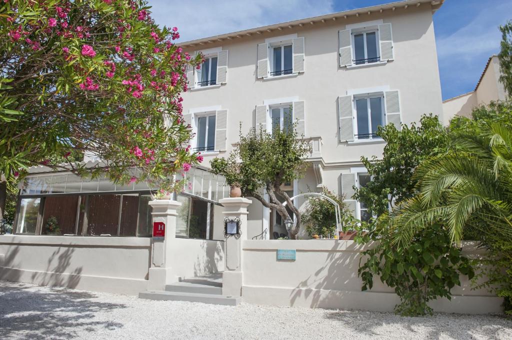 un bâtiment blanc avec des fleurs roses devant lui dans l'établissement Hotel La Bienvenue, à La Croix-Valmer