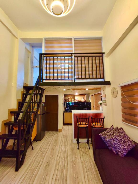 a living room with a staircase and a couch and a kitchen at Loft house @ Patar beach in Bolinao