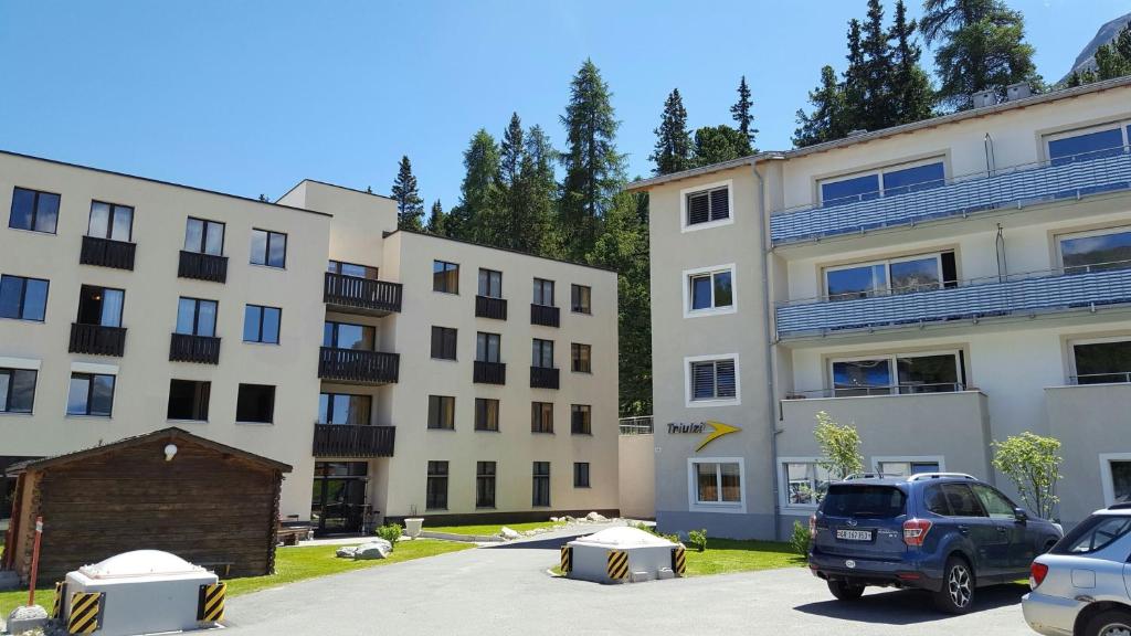 un grupo de edificios con coches estacionados en un estacionamiento en Hotel Stille, en St. Moritz