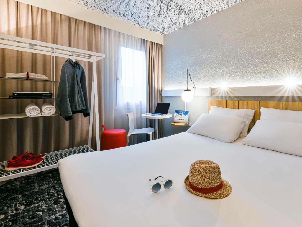 une chambre d'hôtel avec un lit avec un chapeau dessus dans l'établissement ibis Saint Rambert d'Albon, à Saint-Rambert-dʼAlbon