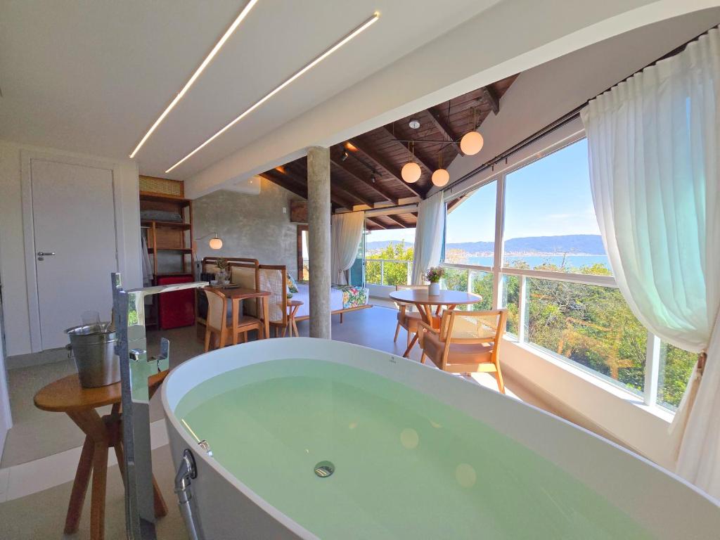 una vasca da bagno in una stanza con una grande finestra di Refúgio da Lagoinha - Centro de Bombinhas a Bombinhas