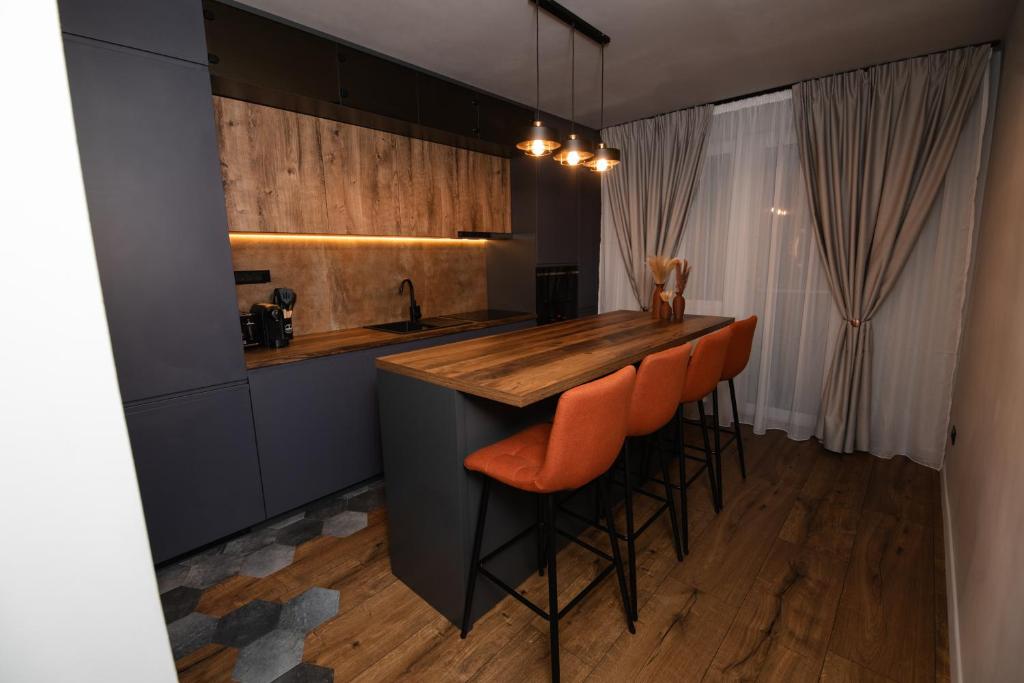 una cucina con un bar con sgabelli da bar arancioni di PNT Noir Apartment a Alba Iulia