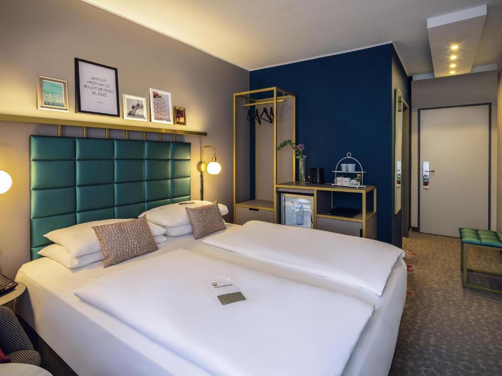 Un dormitorio con dos camas y una pared azul. en Mercure Wien Zentrum, en Viena